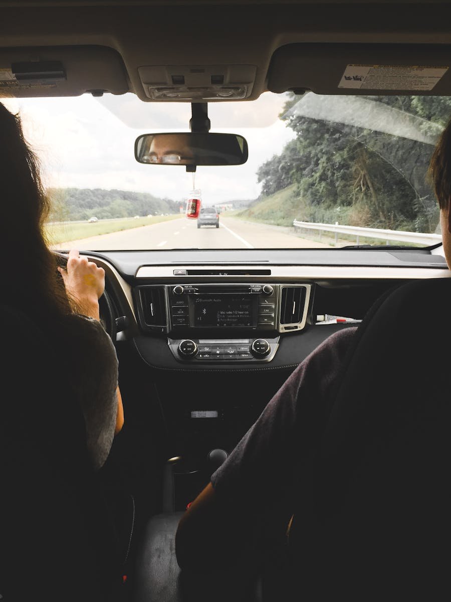 View from inside a car showing passengers looking out at an open highway, emphasizing travel and journey.